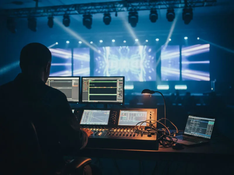 Technician at a sound and lighting console at the back of a corporate conference hall with an LED wall in the background